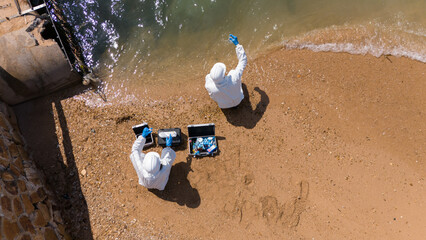 A male and female biologist are analyzing water test results and collecting samples for examination.