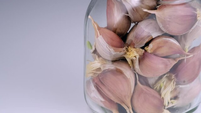 Sprouted garlic in a jar on a white background, close-up.