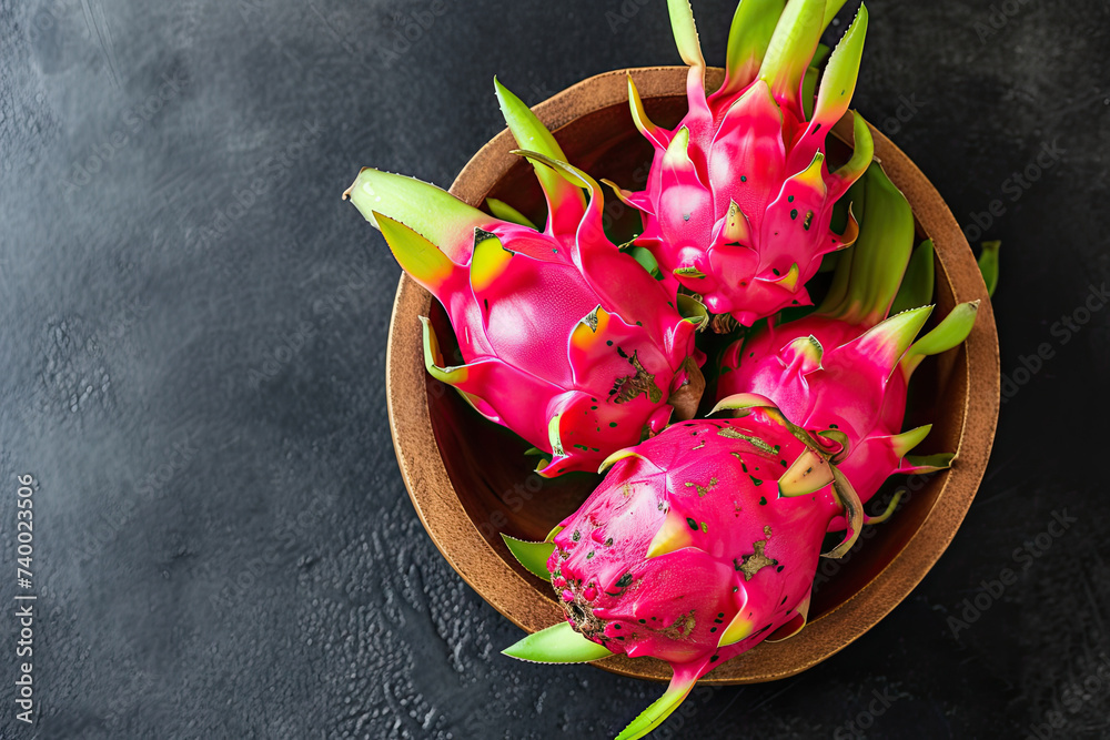 Wall mural top view dragon fruit on the wooden bowl and black table