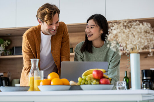 Adult couple using laptop together at kitchen counter
