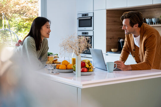 Adult man using laptop while having breakfast with friend