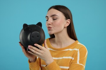 Fototapeta premium Woman with piggy bank on light blue background