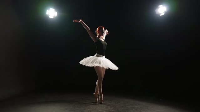 Professional ballerina dancing in studio. Professional ballet dancer young woman in pointe shoes white tutu performing dancing elements of classical ballet. Ballet dance show, sport talent concept.