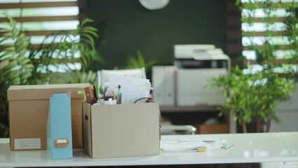 New job. table in modern green office with personal belongings in cardboard box.