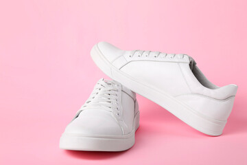 Pair of stylish white sneakers on pink background