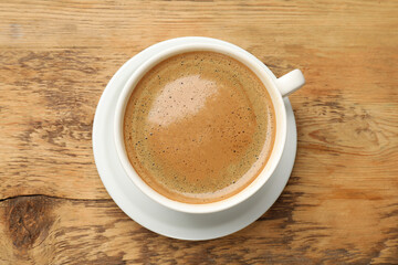Cup of aromatic coffee on wooden table, top view