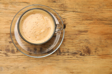 Cup of aromatic coffee on wooden table, top view. Space for text