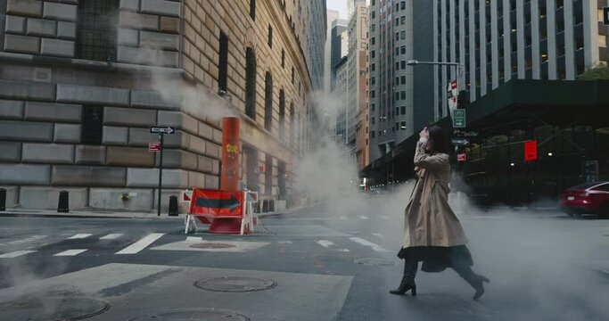 Slow motion of elegant woman crossing the road and walking through the steam from the pipes in urban New York landscape