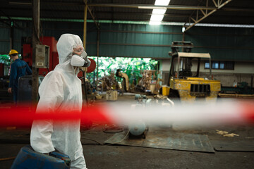Workers wearing safety suits and gas masks under inspection of chemical tanks in industrial work...