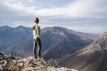 Hiker girl on the mountain top in trip, sport and active life concept, young girl enjoying view on peak of sunny mountain, tourist traveler on background view mockup 