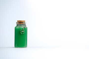 Phial with green liquid and four leaf clover shamrock on white background