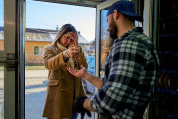 A worried customer delivers car keys to the mechanic at the workshop door, a moment reflecting...