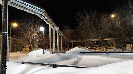 Industrial Metal Pipes on a Snow-Covered City Street at Night During Winter