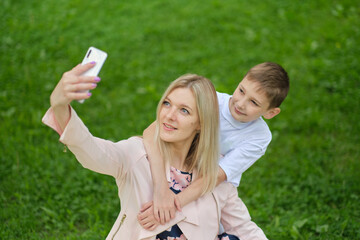 Digital memories: A mother and her teenage boy happily document their time together with a smartphone selfie.