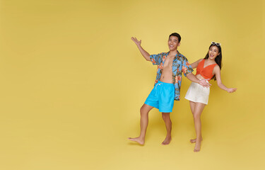 Happy Asian couple traveler dressed in summer clothes open hand welcome holiday trip summer beach isolated on yellow background.