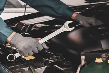 Mechanic works on the engine of the car in the garage.Concept of car inspection service and car...