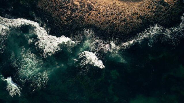 Blue waves of the Atlantic Ocean near the Faro de Toston lighthouse in the Canary Islands. The sea coast of the volcanic island of Fuerteventura surrounded by the sea waves of the Atlantic Ocean, sea 