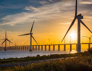 wind turbines at sunset with a bridge in the background