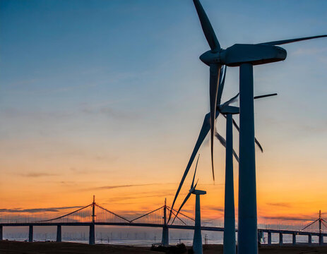 wind turbines at sunset with a bridge in the background