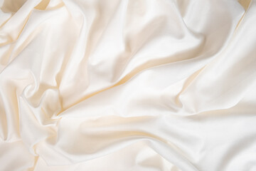 Waves and patterns of crumpled natural satin white milk color fabric.