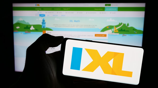 Stuttgart, Germany - 02-08-2024: Person holding cellphone with logo of US online education company IXL Learning Inc. in front of business webpage. Focus on phone display.