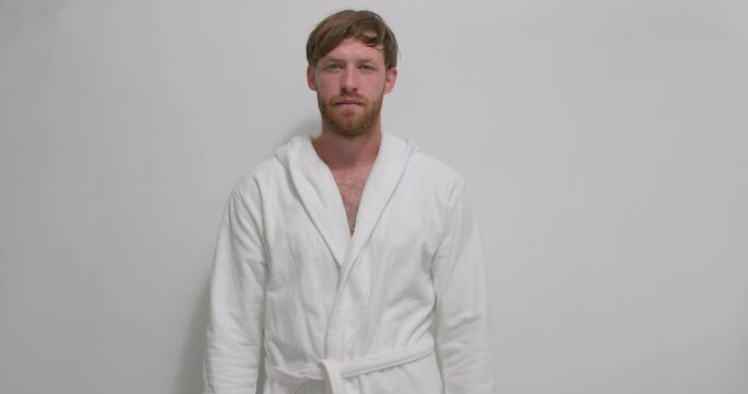 Handsome confident bearded man in white bathrobe posing, looking at camera over white background lifestyle free spare time rest weekend holiday businessman having rest at home closeup portrait