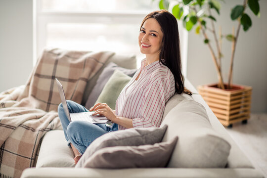 Full body profile photo of cheerful nice lady sit comfy couch use wireless laptop eshopping free time house inside