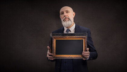 Portrait corporate d'un homme d'affaires en costume et avec barbe qui tient un cadre en ardoise en bois