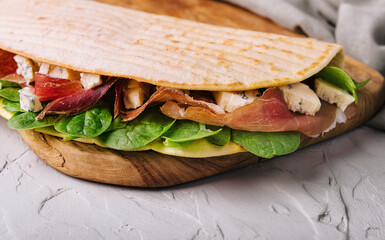 Piadina - classic Italian tortilla-bread with prosciutto, basil and dor blue