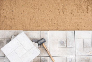 Scene of an ongoing pavement or tile installation. There is a rubber mallet and tiles on top of the...