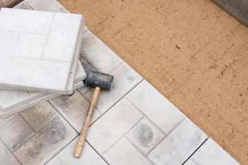 Scene of an ongoing pavement or tile installation. There is a rubber mallet and tiles on top of the...