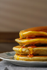 A stack of pancakes with honey on a vintage plate on the table. Breakfast.
