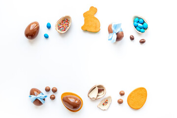 Easter background. Chocolate Easter eggs in blue ribbon with bunny cookies