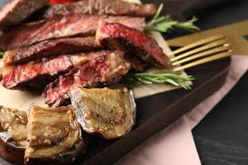 Delicious grilled eggplant and beef with rosemary on table, closeup