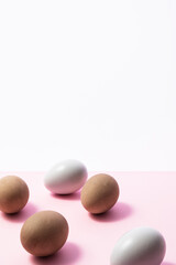 Fototapeta na wymiar Gray painted eggs and brown eggs on pink background