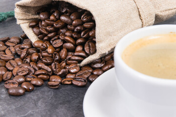 Coffee in white cup and roasted dark coffee beans in bag