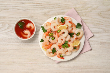 Tasty boiled shrimps with cocktail sauce, chili, parsley and lemon on light wooden table, flat lay