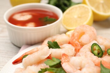 Tasty boiled shrimps with cocktail sauce, chili and parsley on table, closeup