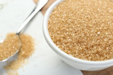 Brown sugar in bowl on white table, closeup