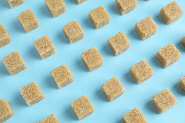 Brown sugar cubes on light blue background