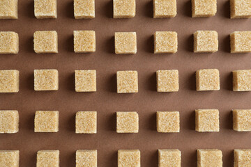 Brown sugar cubes on color background, top view