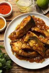 Tasty Indian fish curry on wooden table, flat lay