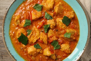 Delicious chicken curry on wooden table, top view