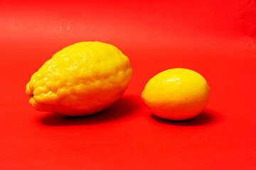 Juicy ripe lemons on a red background. A creative food concept. Tropical organic fruits, citrus fruits, vitamin C. Whole lemon. Summer minimalistic bright fruit background.