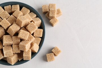 Brown sugar cubes on light table, flat lay. Space for text