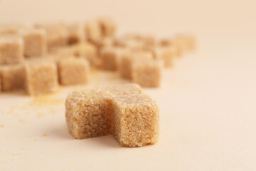 Brown sugar cubes on beige background, closeup. Space for text