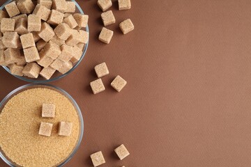 Granulated brown sugar and cubes on color background, flat lay. Space for text