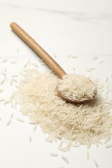 Raw basmati rice with spoon on white table