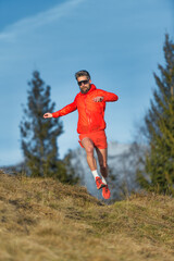 Athlete man runs in mountain meadow