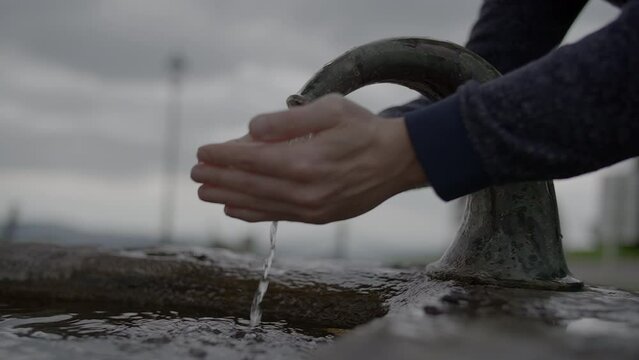 Person Washing Hands Outside at Water Fountain in Slow Motion